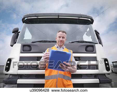 Stock Photo - Portrait of truck driver checking notes on clipboard. Fotosearch