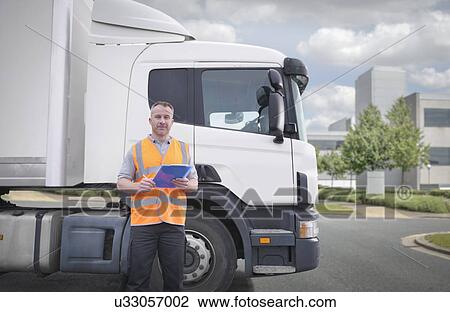 Stock Image - Portrait of truck driver standing by truck. Fotosearch
