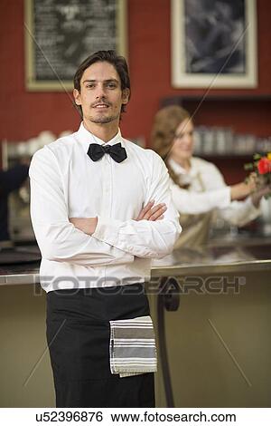 Stock Photograph - Portrait of waiter with arms folded in restaurant. Fotosearch