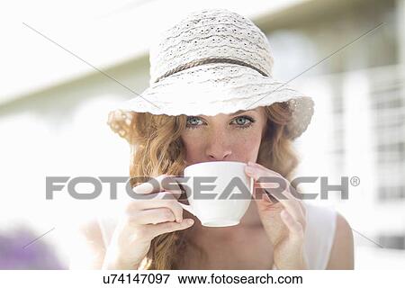 Portrait of young woman drinking from coffee cup at sidewalk cafe View Large Photo Image Stock Photo - Portrait of young woman drinking from coffee cup at sidewalk cafe. Fotosearch