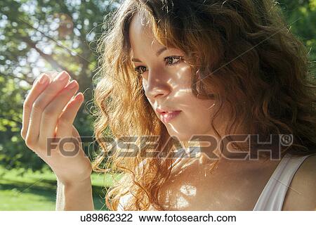 Portrait of young woman gazing at something glowing in hand View Large Photo Image Stock Image - Portrait of young woman gazing at something glowing in hand. Fotosearch