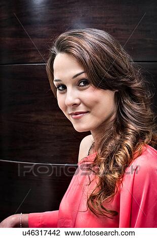 Stock Image - Portrait of young woman in hair salon with long ringletted brunette hair. Fotosearch