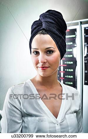Stock Photo - Portrait of young woman in hair salon with towel wrapped around her head. Fotosearch