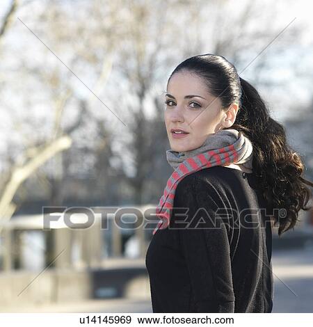 Portrait of young woman looking over her shoulder View Large Photo Image Stock Photo - Portrait of young woman looking over her shoulder. Fotosearch