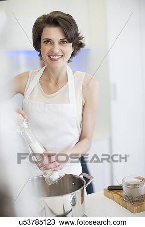 Portrait of young woman using salt mill whilst cooking in kitchen View Large Photo Image Stock Image - Portrait of young woman using salt mill whilst cooking in kitchen. Fotosearch