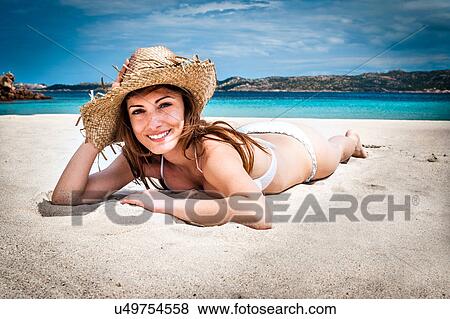Portrait of young woman wearing bikini and sunhat lying on beach, La Maddalena, Sardinia, Italy View Large Photo Image Stock Photo - Portrait of young woman wearing bikini and sunhat lying on beach, La Maddalena, Sardinia, Italy. Fotosearch