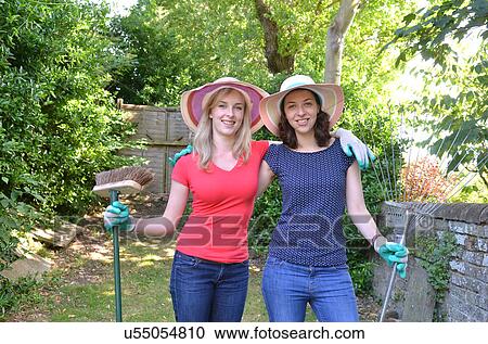 Stock Image - Portrait of young women holding gardening equipment. Fotosearch