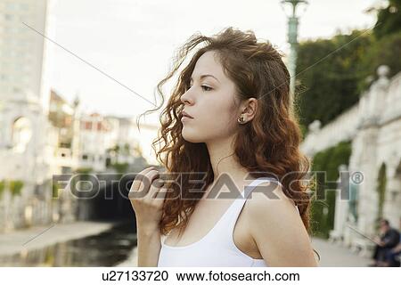 Stock Image - Profile portrait of sullen young woman in city. Fotosearch