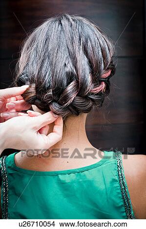 Picture - Rear view of female hairdresser braiding young woman's hair in hair salon. Fotosearch