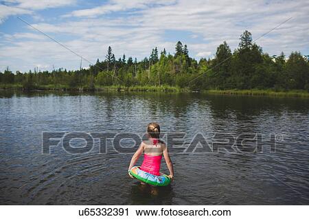 Stock Image - Rear view of girl with rubber ring in Indian river, Ontario, Canada. Fotosearch