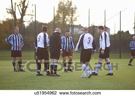 Stock Image - Referee and football players settling dispute. Fotosearch