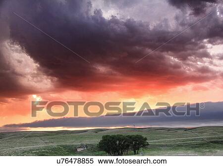 Stock Photography - Roll cloud hangs low in the distance with sunset colors reflecting ongoing storm convection, Lexington, Nebraska, USA. Fotosearch