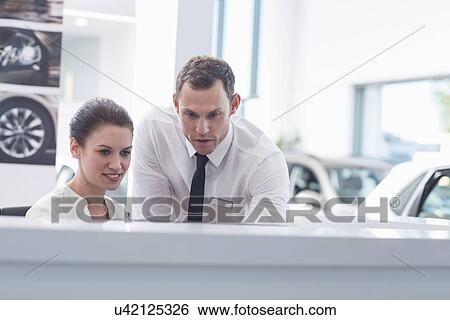 Salesman and saleswoman at desk in car dealership View Large Photo Image Stock Photograph - Salesman and saleswoman at desk in car dealership. Fotosearch
