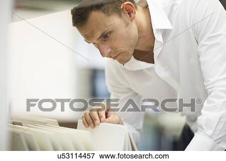 Salesman searching in filing cabinet in kitchen showroom View Large Photo Image Stock Photo - Salesman searching in filing cabinet in kitchen showroom. Fotosearch