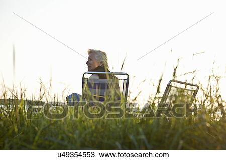 Stock Image - Senior woman relaxing by beach. Fotosearch