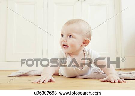 Stock Image - Smiling baby boy crawling on floor. Fotosearch