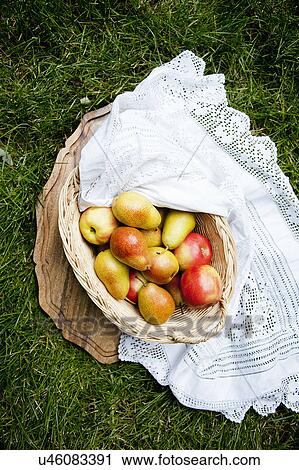 Stock Image - Still life with basket of apples and pears on grass. Fotosearch