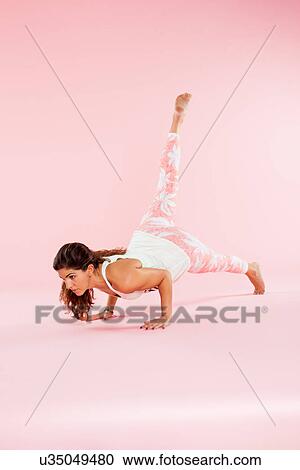Studio shot of young woman in yoga position balancing with hands on floor and leg raised View Large Photo Image Stock Image - Studio shot of young woman in yoga position balancing with hands on floor and leg raised. Fotosearch