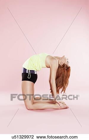 Studio shot of young woman in yoga position kneeling and bending backwards View Large Photo Image Stock Image - Studio shot of young woman in yoga position kneeling and bending backwards. Fotosearch