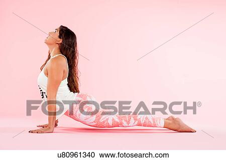 Stock Image - Studio shot of young woman in yoga position with hands on floor. Fotosearch
