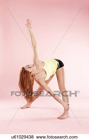 Stock Photo - Studio shot of young woman in yoga position twisting with arm raised. Fotosearch