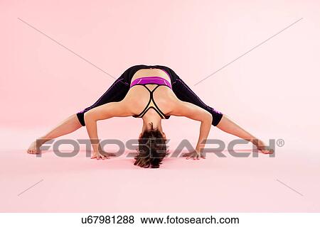Studio shot of young woman in yoga position leaning forward with legs outstretched View Large Photo Image Stock Photo - Studio shot of young woman in yoga position leaning forward with legs outstretched. Fotosearch