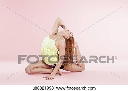 Studio shot of young woman in yoga position bending backwards on floor touching toes View Large Photo Image Stock Photo - Studio shot of young woman in yoga position bending backwards on floor touching toes. Fotosearch