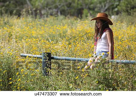 Sullen girl in cowboy hat sitting on fence in field View Large Photo Image Stock Photo - Sullen girl in cowboy hat sitting on fence in field. Fotosearch