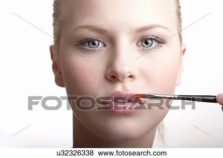 Stock Photo - Teenage girl applying lip gloss. Fotosearch