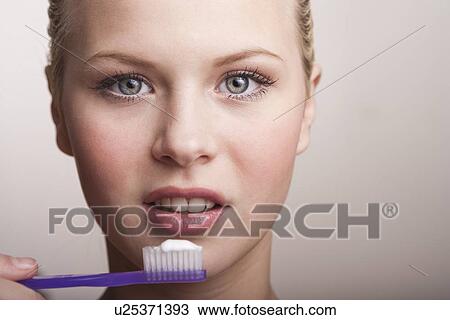 Stock Image - Teenage girl brushing teeth. Fotosearch