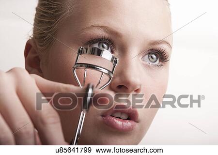 Stock Photo - Teenage girl using eyelash curlers. Fotosearch