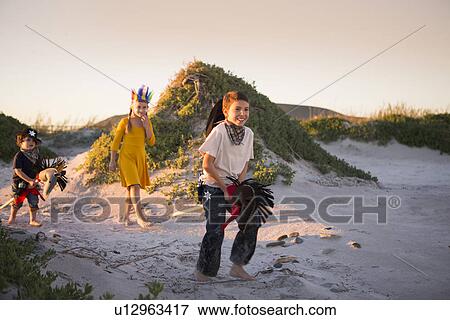 Three children dressed as native american and cowboys running in sand dunes View Large Photo Image Stock Photo - Three children dressed as native american and cowboys running in sand dunes. Fotosearch