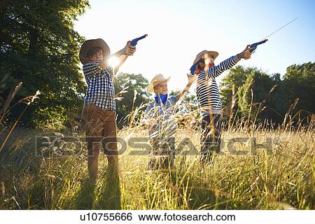 Three young boys dressed as cowboys, holding toy guns View Large Photo Image Stock Photograph - Three young boys dressed as cowboys, holding toy guns. Fotosearch