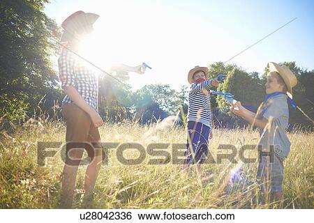 Stock Photograph - Three young boys dressed as cowboys, holding toy guns. Fotosearch
