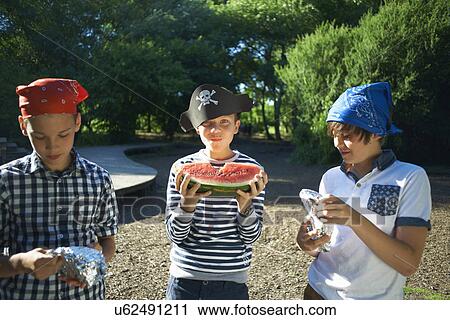 Stock Image - Three young boys having lunch in park. Fotosearch