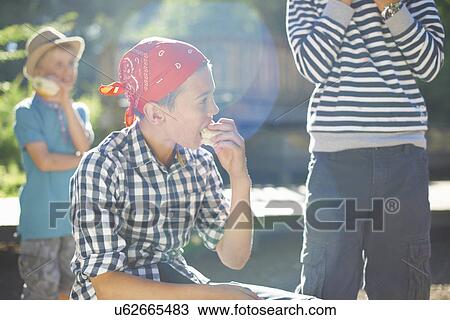 Stock Image - Three young boys having lunch in park. Fotosearch