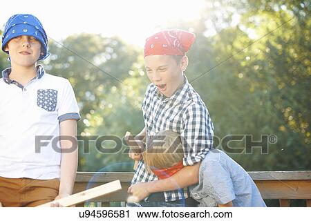 Stock Image - Three young boys playing together in park. Fotosearch