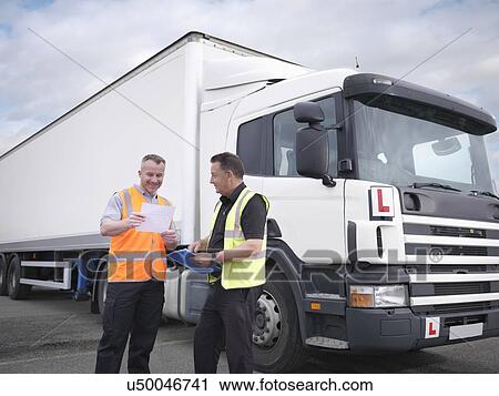 Stock Image - Trainee truck driver receiving pass certificate from instructor. Fotosearch
