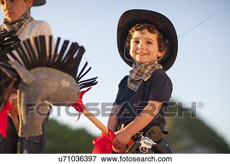 Stock Photo - Two brothers dressed as cowboys on hobby horses. Fotosearch