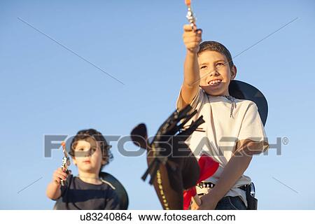 Two brothers dressed as cowboys pointing toy guns View Large Photo Image Picture - Two brothers dressed as cowboys pointing toy guns. Fotosearch