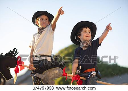 Two brothers dressed as cowboys pointing from sand dunes View Large Photo Image Stock Image - Two brothers dressed as cowboys pointing from sand dunes. Fotosearch