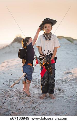 Stock Photo - Two brothers dressed as cowboy's reaching for hat. Fotosearch