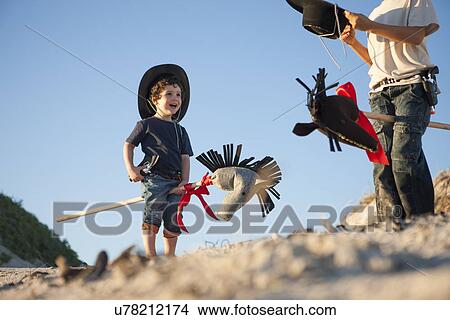 Two brothers dressed as cowboys with hobby horses in sand View Large Photo Image Picture - Two brothers dressed as cowboys with hobby horses in sand. Fotosearch