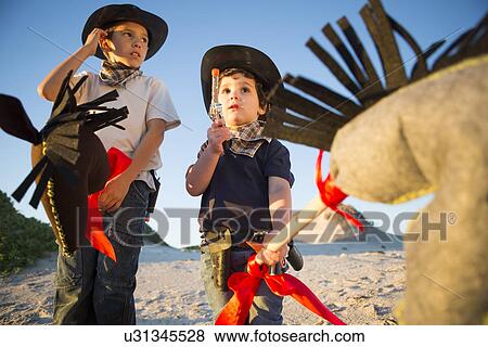 Two brothers dressed as cowboys with toy gun and hobby horse's View Large Photo Image Stock Photo - Two brothers dressed as cowboys with toy gun and hobby horse's. Fotosearch