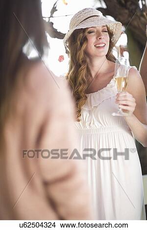 Picture - Two female friends chatting and laughing in garden wine bar. Fotosearch