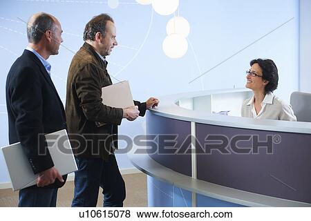 Two mature adult men speaking to receptionist View Large Photo Image Stock Photo - Two mature adult men speaking to receptionist. Fotosearch