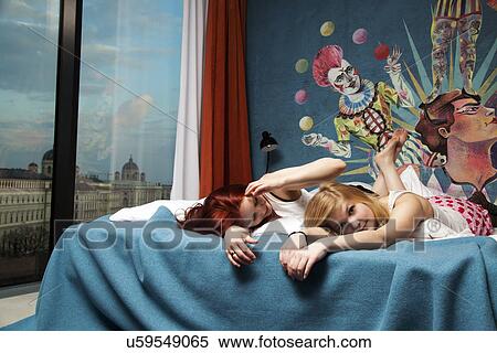 Two sleepy young women lying on hotel bed View Large Photo Image Stock Photography - Two sleepy young women lying on hotel bed. Fotosearch