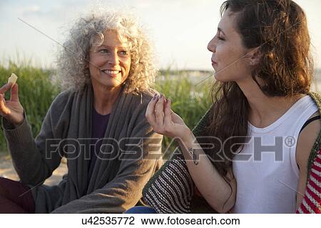 Stock Image - Two women having picnic on Bournemouth beach, Dorset, UK. Fotosearch