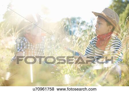 Stock Photo - Two young boys dressed as cowboys, holding toy guns. Fotosearch
