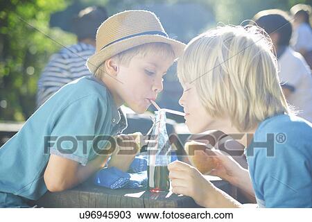 Two young boys drinking from bottle with straws View Large Photo Image Stock Image - Two young boys drinking from bottle with straws. Fotosearch